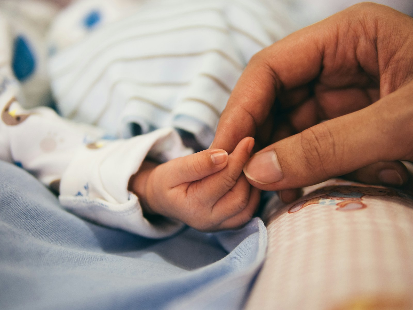 Newborn hand holding a parent's finger
